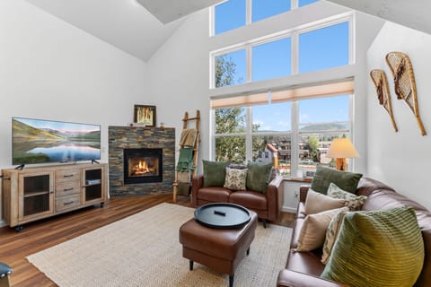 Sink into plush leather seating by your cozy fireplace, soaking in mountain views through soaring windows that flood this stunning living space with natural light and unforgettable scenery.