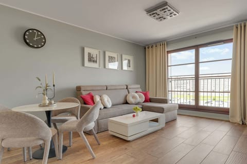 W strefie wypoczynkowej znajduje się wygodna narożna sofa, która może pełnić funkcję dodatkowego miejsca do spania, stolik kawowy oraz telewizor z funkcją Smart TV.