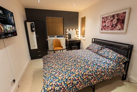 Playful floral bedroom with lit vanity and mounted TV