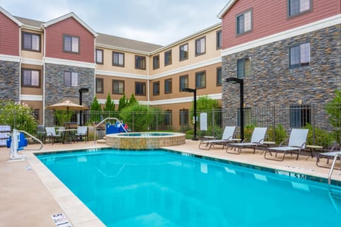 Outdoor pool with lounge chairs and surrounding greenery - open seasonally from 8 AM to 10 PM