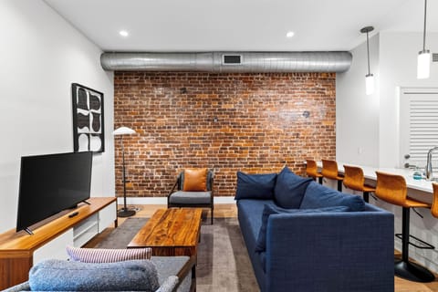 Relax in the modern living area, featuring exposed brick and a sleeper sofa for additional guests.