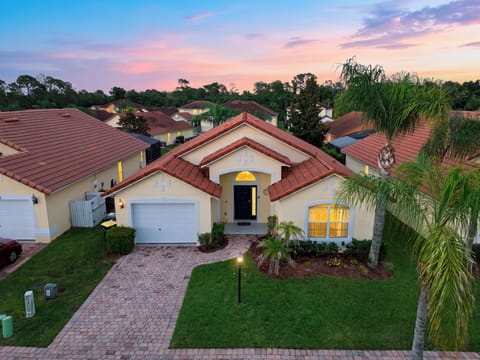Gorgeous dusk exterior shot of the home showing warm interior lights and lush green lawn.