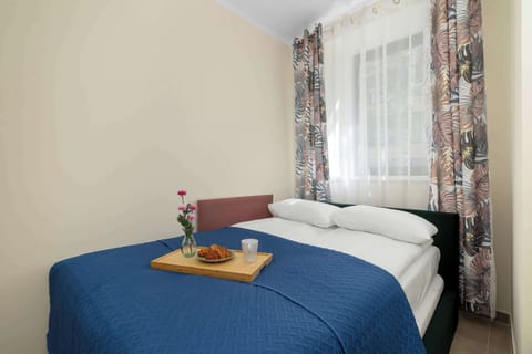 A cozy bedroom with a neatly made double bed, blue bedding, and a small breakfast tray placed on top.