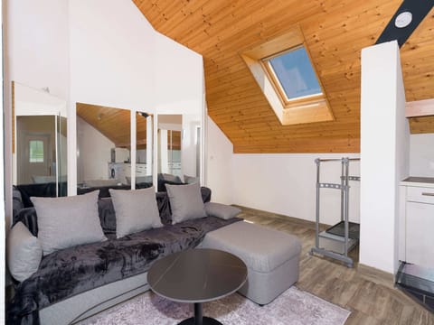 Bright attic-style living room with comfortable seating, skylight, and warm wooden ceiling details.
