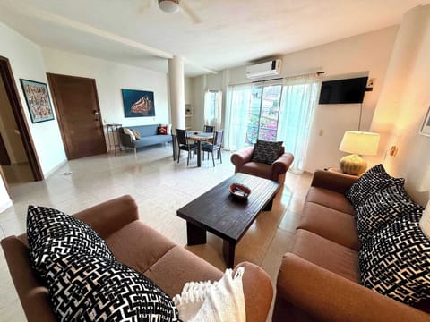 Spacious living room with smart tv, AC, ceiling fan, and lots of seating options.