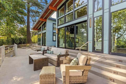 The patio off the living room and primary suite. This multi level patio features several seating areas, dining space, grill, hot tub, sauna and trails to the river. 