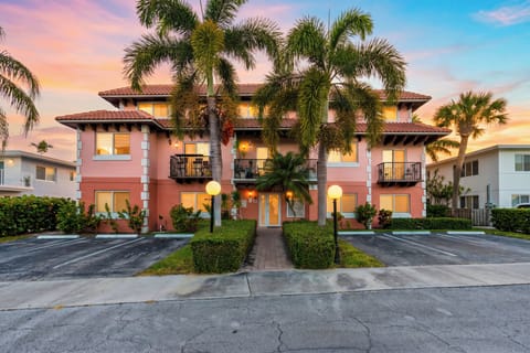 Tropical townhome exterior with palm-lined entry, private balconies, and warm sunset curb appeal.