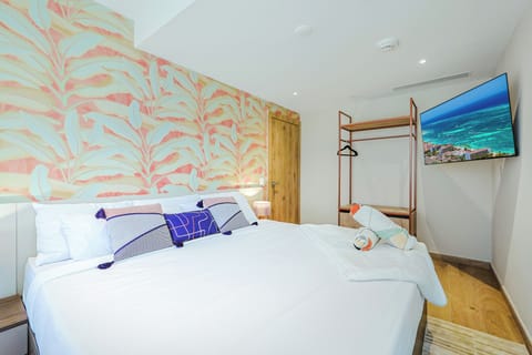 Your bright, contemporary bedroom features a plush king bed, tropical-inspired accent wall, and warm wood floors—everything set for a restful stay in style.