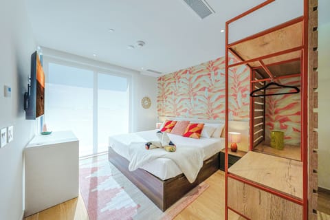 Step into your sunlit bedroom where a plush bed awaits and a unique tropical mural brings vibrant warmth to the space—perfect for unwinding after a day of adventure.