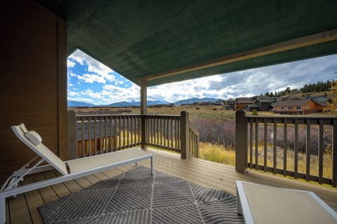 Covered deck with mountain views and open grasslands framing the property's natural setting—ideal for outdoor relaxation in this secluded retreat.