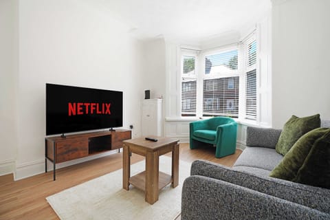 Relax in the bright and inviting living room, featuring a comfortable sofa, an armchair by the bay window, a coffee table, a Smart TV, and free Wi-Fi. It's the perfect space to unwind with family, friends, or colleagues after a busy day.