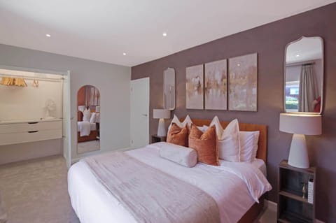 Plush zip & link bed that can be set up as king-size bed or 2 single beds, with premium linens, bedside tables with lamps, and elegant décor, creating a warm and relaxing retreat for a restful night's sleep.