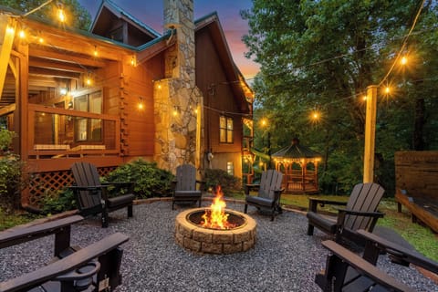 Fire pit burning at dusk with chairs pulled in close and string lights overhead. The gathering spot every night, no matter what the day's plan was.