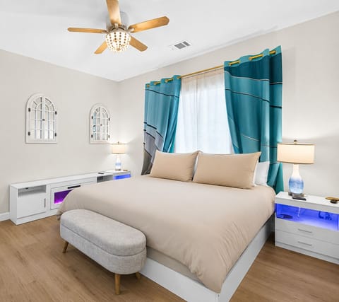 Bright modern bedroom with king bed, teal accents, and cozy seating bench