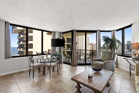 The living room has a panoramic view through the large glass window showcases the Gulf and fills the room with natural light, while direct access to the balcony lets guests step outside to enjoy the breeze.