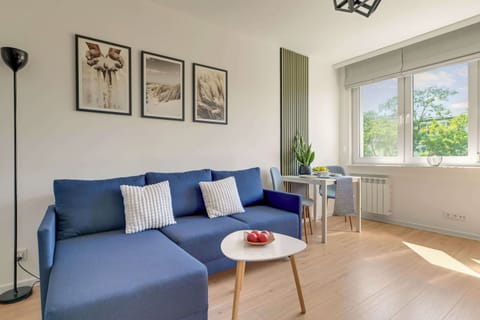 Salon jest jasną i komfortową przestrzenią wypoczynkową połączoną z aneksem kuchennym. Znajduje się w nim podwójna rozkładana sofa, stolik kawowy, Smart TV oraz stół jadalniany z krzesłami.