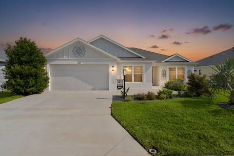 A charming single-story property nestled in a well-maintained neighborhood, photographed as the sky transitions from day to dusk. The home features a spacious driveway and welcoming landscaped yard in a peaceful residential setting.