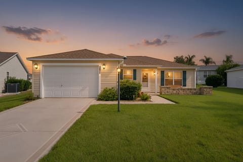 This inviting single-story home sits on a quiet residential street in a well-maintained neighborhood, with warm evening light highlighting its welcoming facade and spacious front lawn.