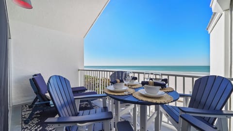 Private oceanfront balcony with dining setup and sweeping beach views
