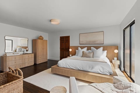 Generous bedroom layout with storage, warm wood floors, and elevated neutral decor.