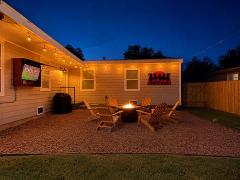 Cozy backyard retreat with fire pit, string lights, grill & outdoor TV