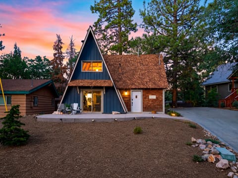 Exterior shot of the wooden A-frame cabin lit up at dusk.