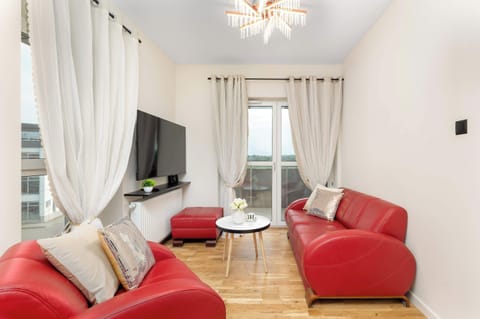 Stylish living room with red leather sofas, a coffee table, TV, and elegant décor.
