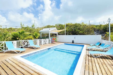 Wooden deck with loungers and gazebo, surrounded by tropical landscaping