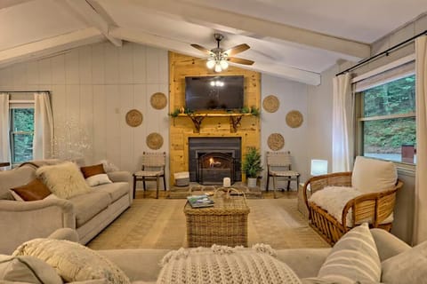 Cozy vaulted living room with fireplace, big TV, and serene wooded views
