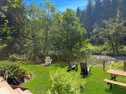 Outdoor dining table, comfy seats, firepit, hammock, green grass, river access