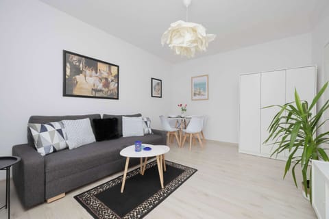 Bright living room with a comfortable sofa, coffee table, TV, dining area, and modern décor.