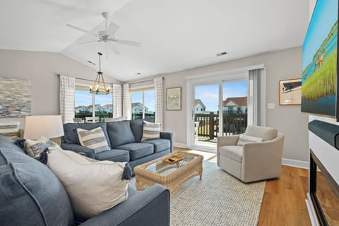 Sink into plush sofas in your bright living room, where coastal breezes flow through balcony doors and natural light creates the perfect retreat.
