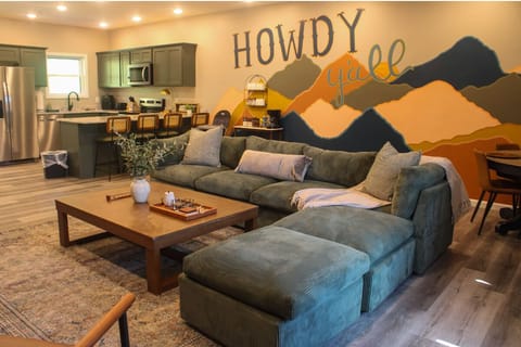 Settle into your open-concept retreat where a plush sectional invites you to unwind beneath playful mountain art. The fully-equipped kitchen and warm, welcoming vibe make this space perfect for gathering.