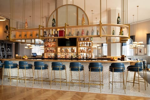 Circular bar counter with tall stools and backlit shelves of spirits