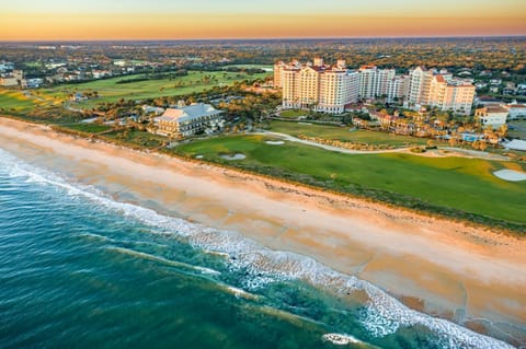 Golden sands and rolling Atlantic waves at sunset, with the resort tower and golf greens behind
