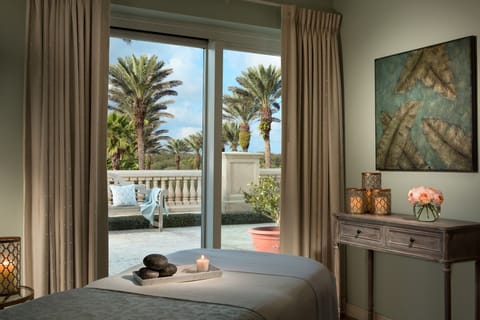 Spa treatment room with a massage table, smooth stones, and a candlelit setting