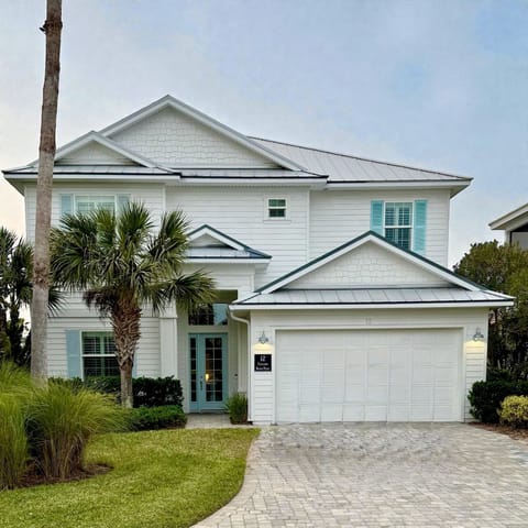 Multi-story exterior with covered lanai, lush landscaping, and direct access to the waterfront pool