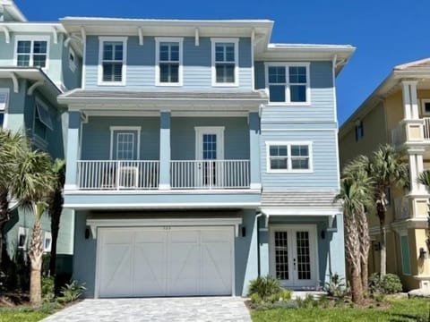 Spacious multi-story home with a private garage, covered balconies, and charming palm-lined entrance