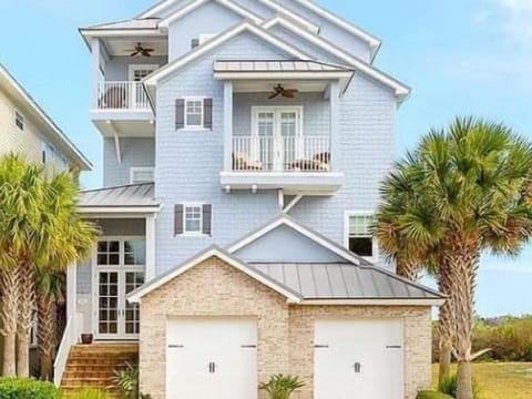 Elegant coastal home with a welcoming entrance, covered balconies, and palm-lined surroundings