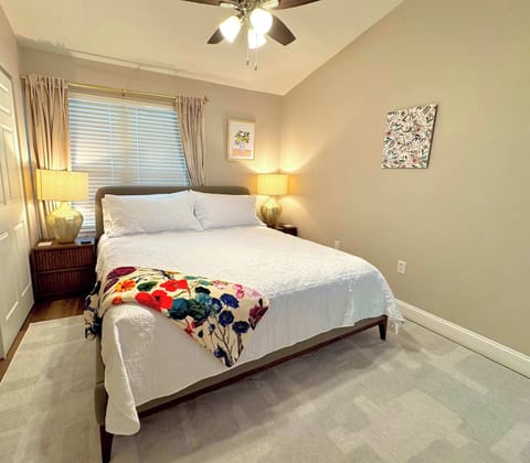 Bedroom with premium Helix Midnight Luxe king mattress and bedding, convenient nightstands (easy access to outlets and multi-compatible charging station), room-darkening shades and curtains, and cozy area rug. 