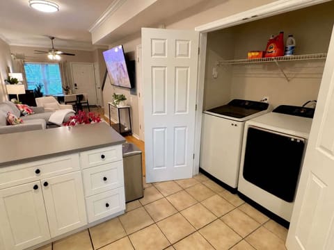 Kitchen with in-unit Samsung washer and dryer located behind French doors. Storage for the provided kitchenware and easy access to the living room. 