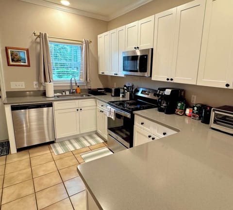 Brightly-lit kitchen with large sink, stovetop, oven, microwave, dishwasher, K-Cup coffee maker, kettle, blender, toaster, refrigerator, freezer, ice maker, and slow-closing drawers and cabinets for provided kitchenware. 