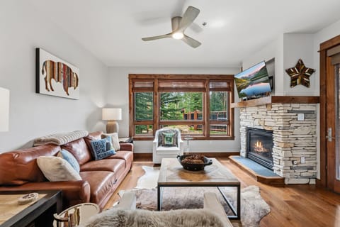 Sink into the leather sofa and feel right at home in this inviting living room, where natural light pours through wood-framed windows and a cozy fireplace awaits to warm your evenings.