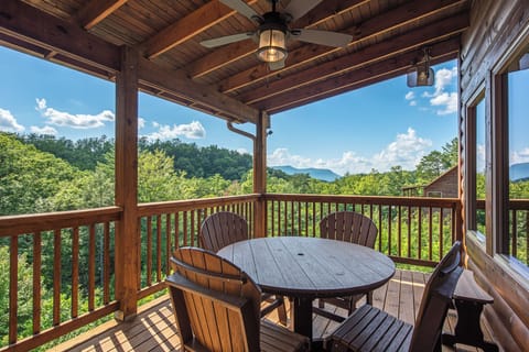 Enjoy your morning coffee on this covered deck, surrounded by lush forest and distant mountain views. The outdoor dining table invites you to savor meals in fresh air.