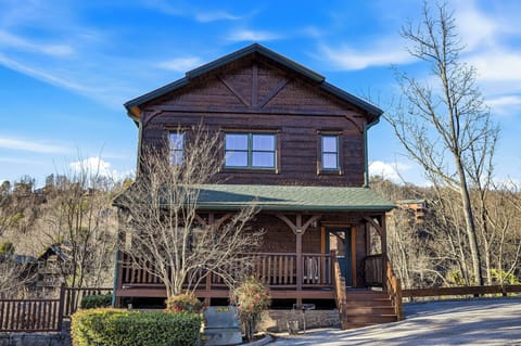 A charming rustic cabin with covered porch and mountain architecture provides a peaceful retreat in a scenic hillside setting.