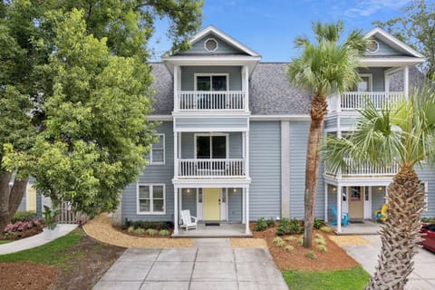 This charming multi-level coastal property features private balconies, a palm-lined entrance, and inviting communal spaces perfect for your beach getaway.