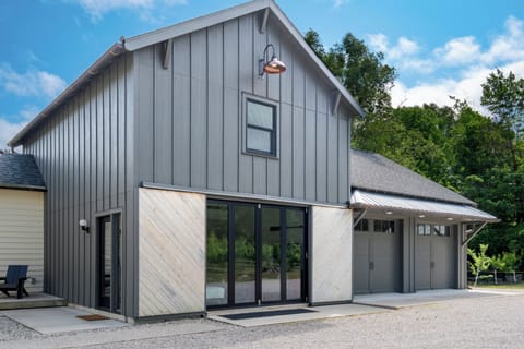 Modern barn-style retreat with garage, glass doors, and wooded views