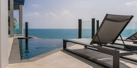 Sunbathe beside the infinity pool above sparkling blue water.