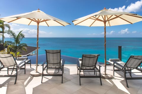 Lounge under oversized umbrellas while the turquoise sea sparkles.