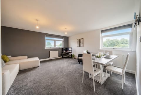Bright open living and dining space with leafy views and a comfy corner sofa.